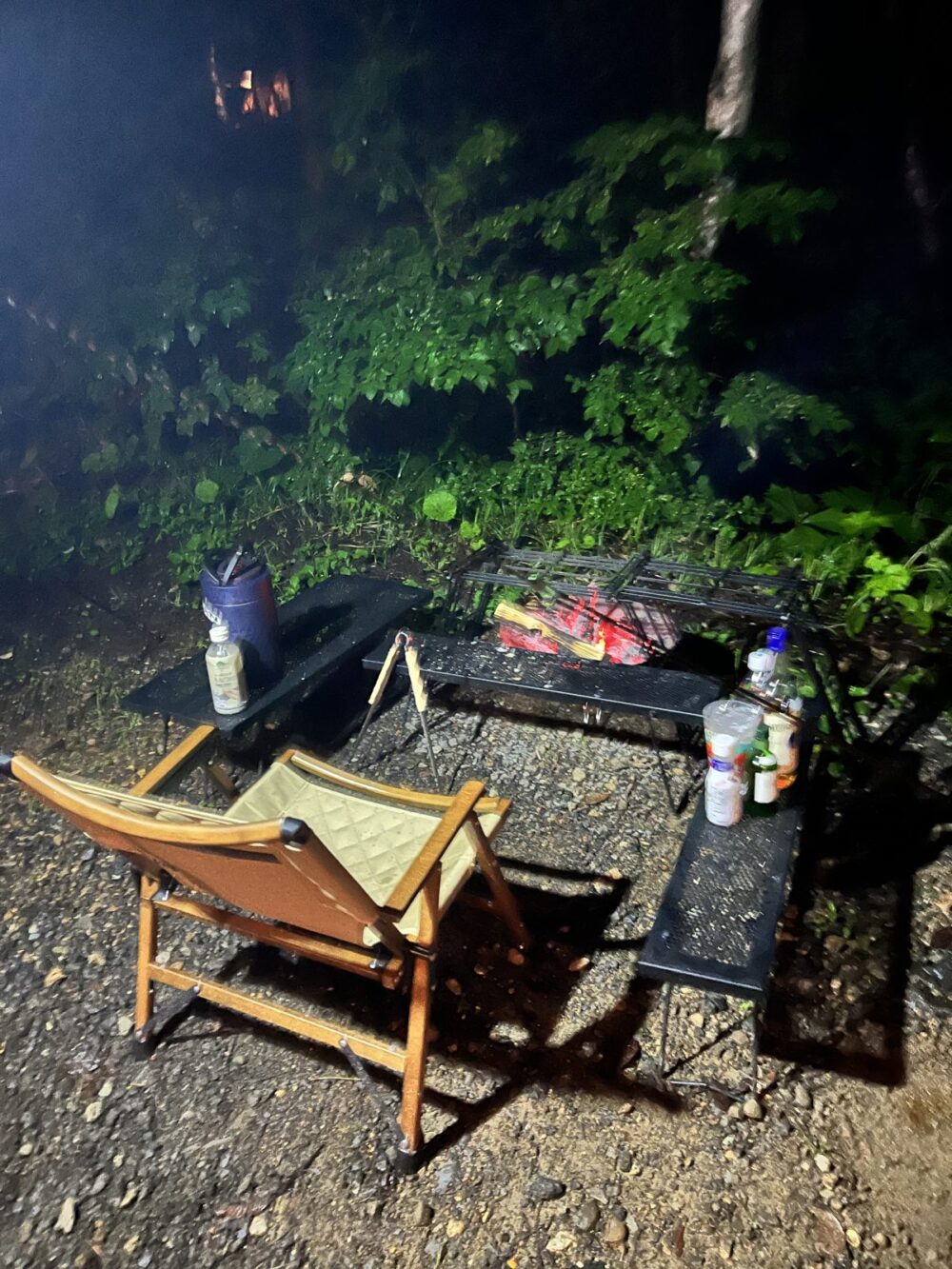夜のキャンプサイトで焚き火台の前に置いた折りたたみチェア